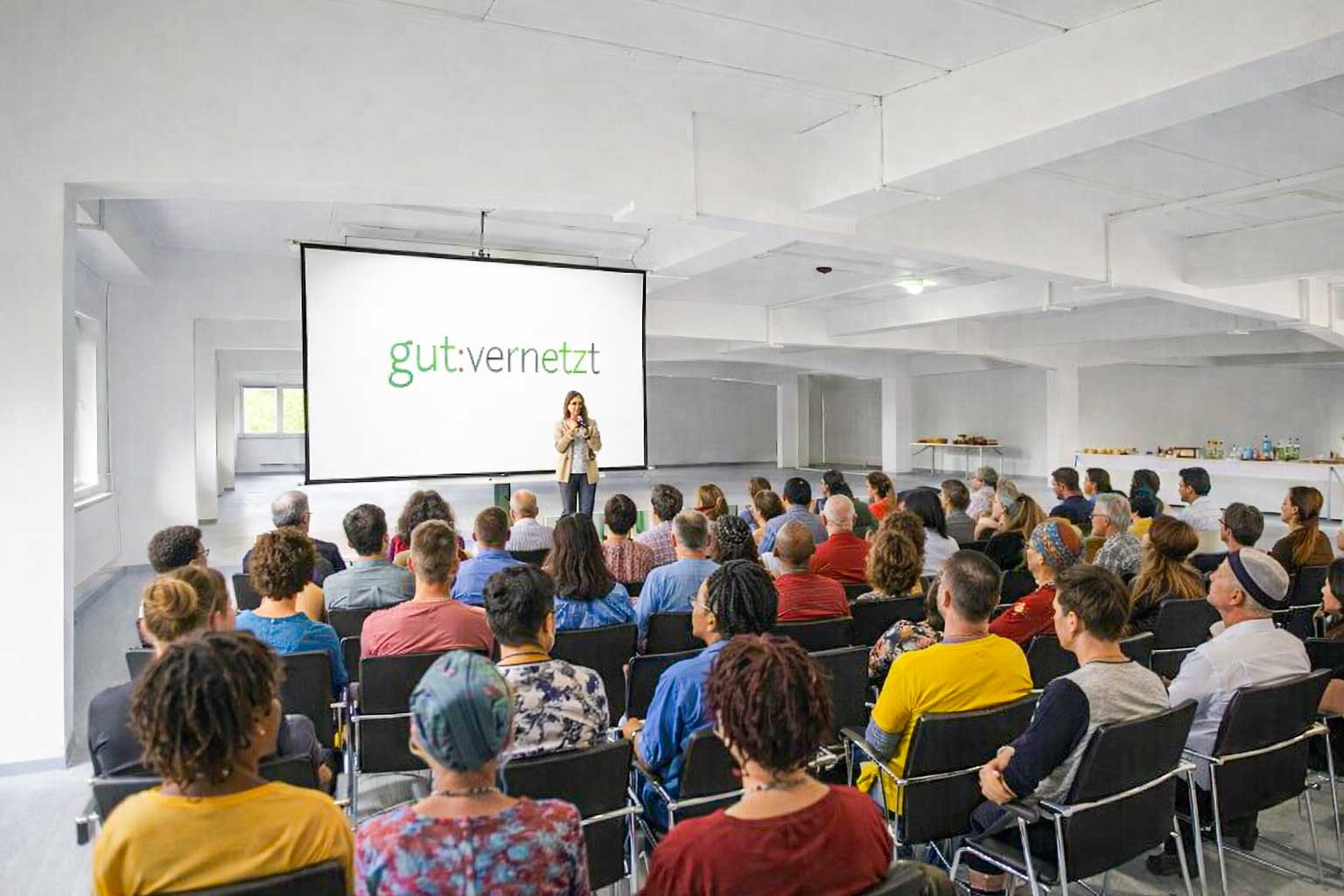 KI-Bild mit vielfältigen menschen vor einer Leinwand, auf der gut:vernetzt steht für 2. Netzwerktreffen für Kunst und Kultur in Oberhavel